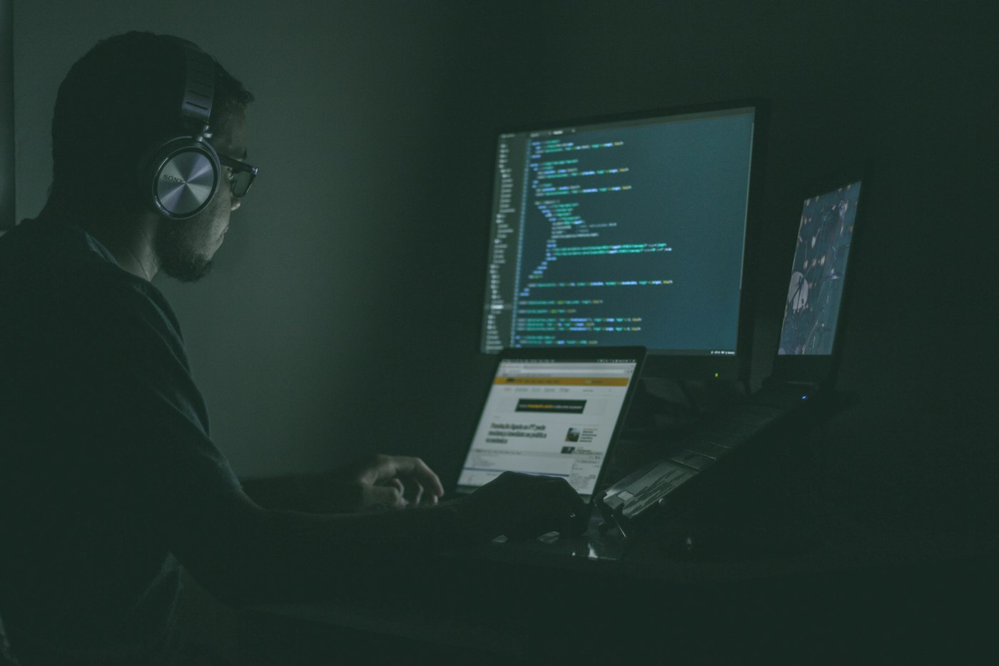A security professional working through code on multiple monitors